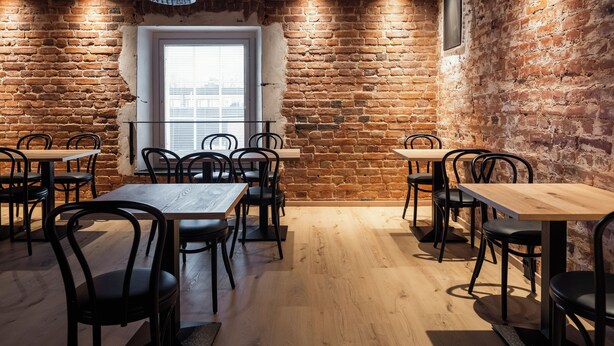 A dining area with brick walls, wooden tables, and black chairs. - Frans&Frans hotel and apartments (Rauma)