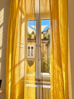 A doorway with yellow curtains, a window, and a view of buildings outside. - Terrace Charming 3-bedroom apartment with WiFi, AC in Campo dei Fiori in Rome (Roma)