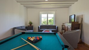 Ein Billardtisch mit Kugeln, zwei Sofas, ein Fernseher und ein Fenster mit Blick.