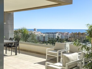A balcony with a table and chairs, overlooking a coastal cityscape. - Modern apartment with terrace, pool, and Wi-Fi in Estepona (Estepona)