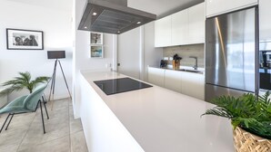 A modern kitchen with a large island, stainless steel appliances, and minimalist design. - Modern apartment with terrace, pool, and Wi-Fi in Estepona (Estepona)