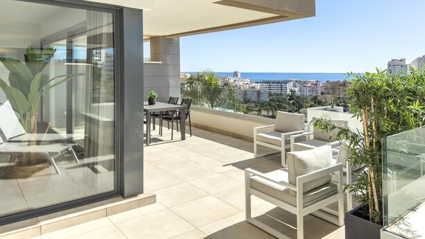 A modern balcony with a glass door, a dining table, and two white chairs. - Modern apartment with terrace, pool, and Wi-Fi in Estepona (Estepona)