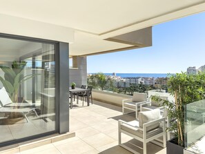 Ein moderner Balkon mit Glastür, einem Esstisch und zwei weißen Stühlen.