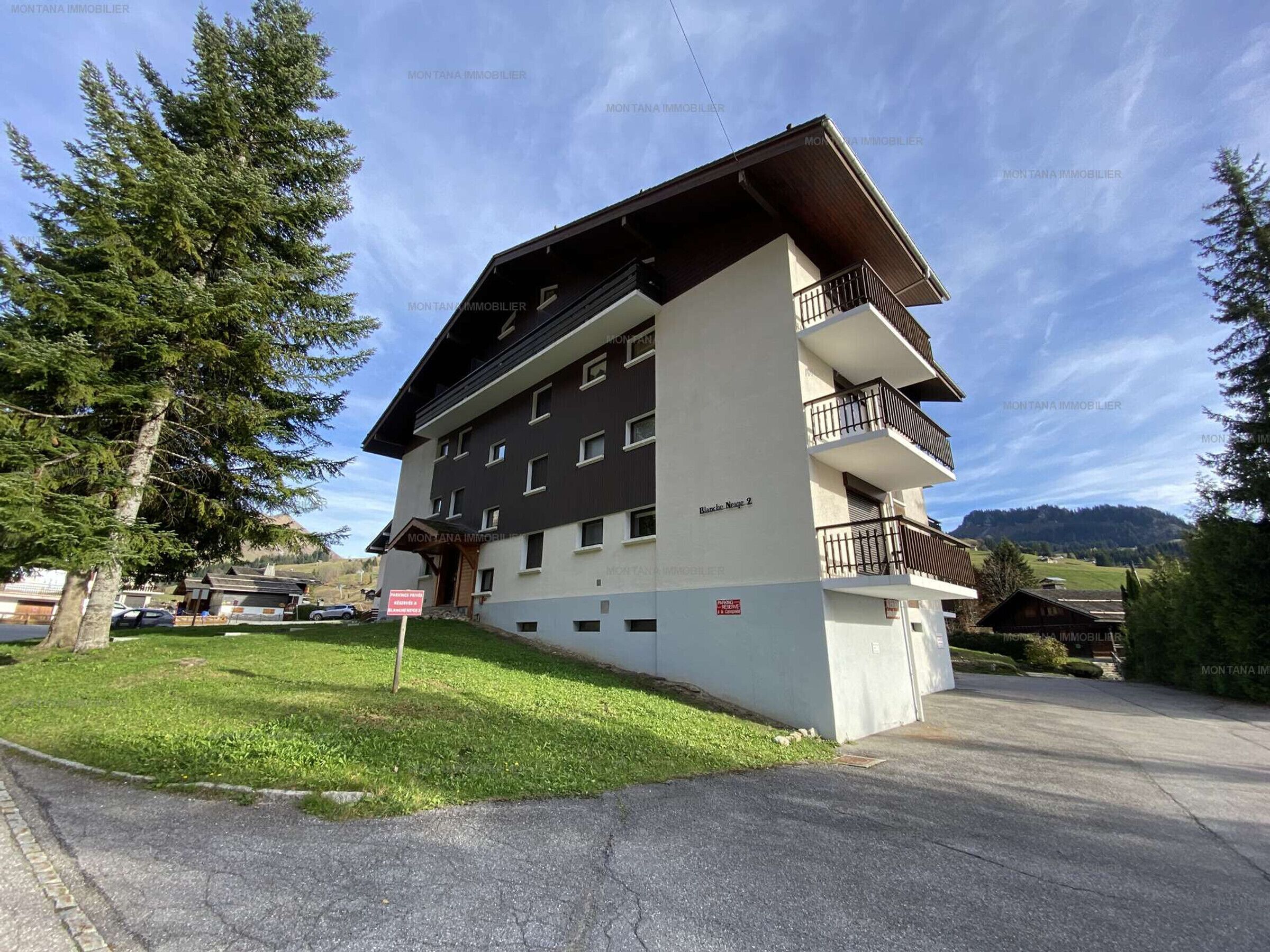 Un immeuble à plusieurs étages doté de balcons, une enseigne indiquant un espace de stationnement et une vue sur le paysage environnant.