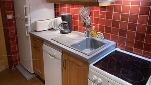 A compact kitchen with wooden cabinets, a built-in microwave, a toaster, a coffee maker, a sink with a faucet, and a stove. - Spacious 2-room apartment for 5 people in Chinaillon (Le Grand-Bornand)
