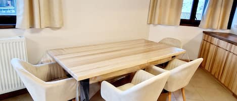 Un comedor con una mesa de madera y cuatro sillas blancas.
