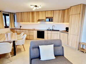 Una cocina moderna con armarios de madera, microondas integrado y zona de comedor con mesa y sillas.