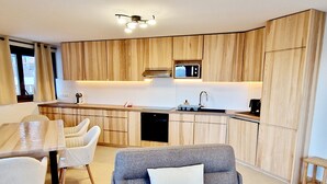 Una cocina moderna con armarios de madera, microondas integrado y zona de comedor con mesa y sillas.