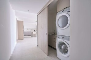 Ein moderner Waschraum mit zwei Waschmaschinen, einer Arbeitsplatte und einer Holztür.