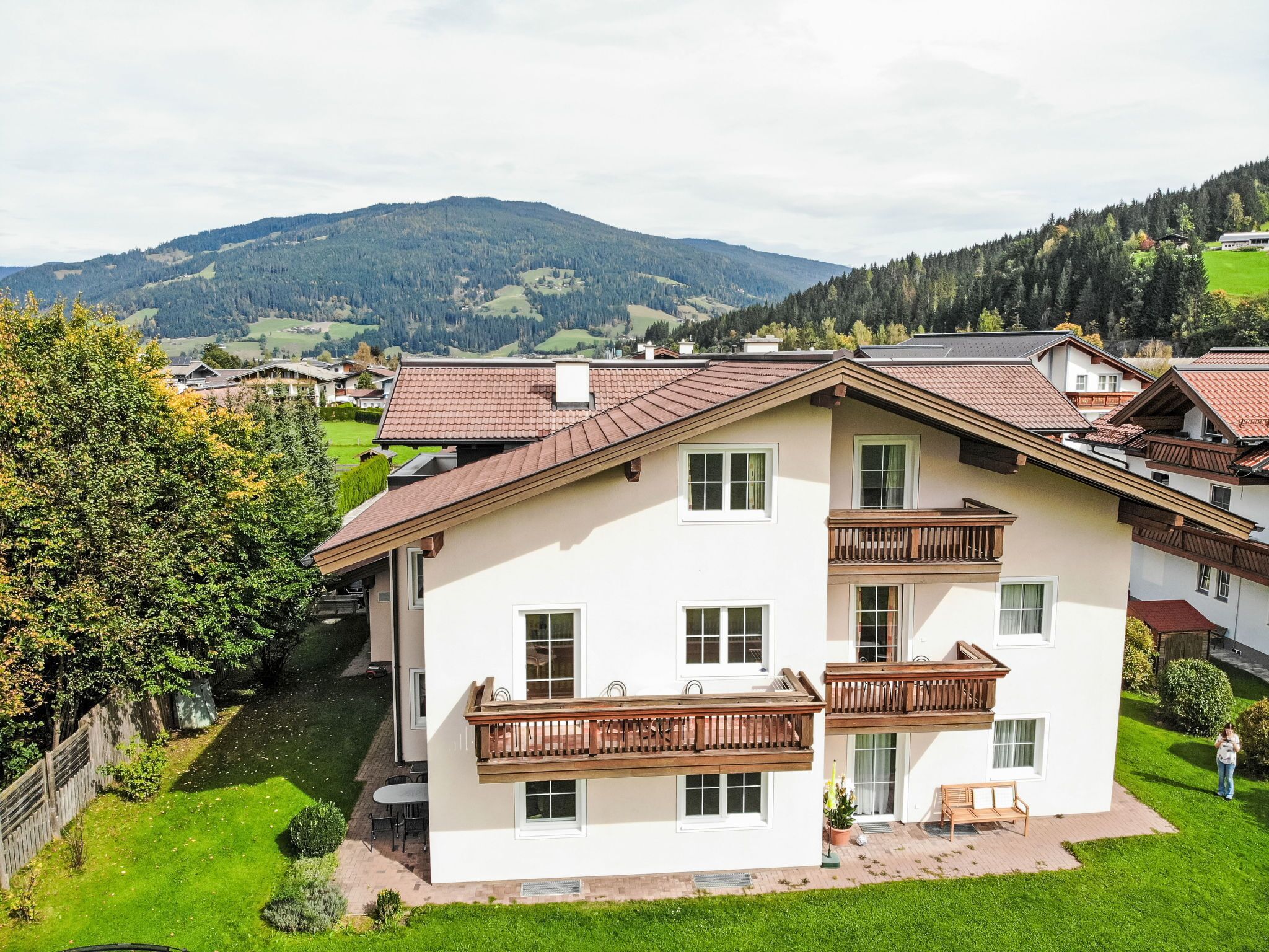 A multi-story residential building with a sloped roof, balconies, and a well-maintained lawn.