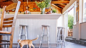 A cat walking past a bar area with stools and a wooden ceiling. - Julia Hotel (Kassandra)