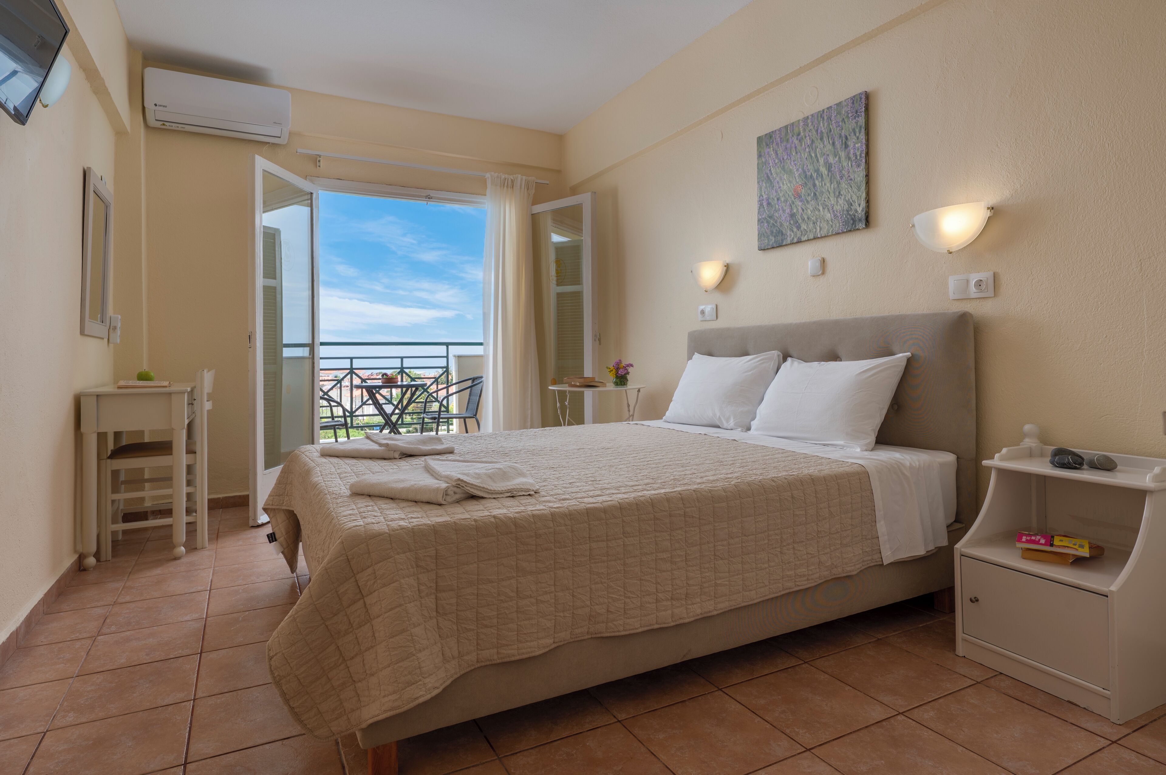A bedroom with a bed, bedside table, and a view of the outside balcony.