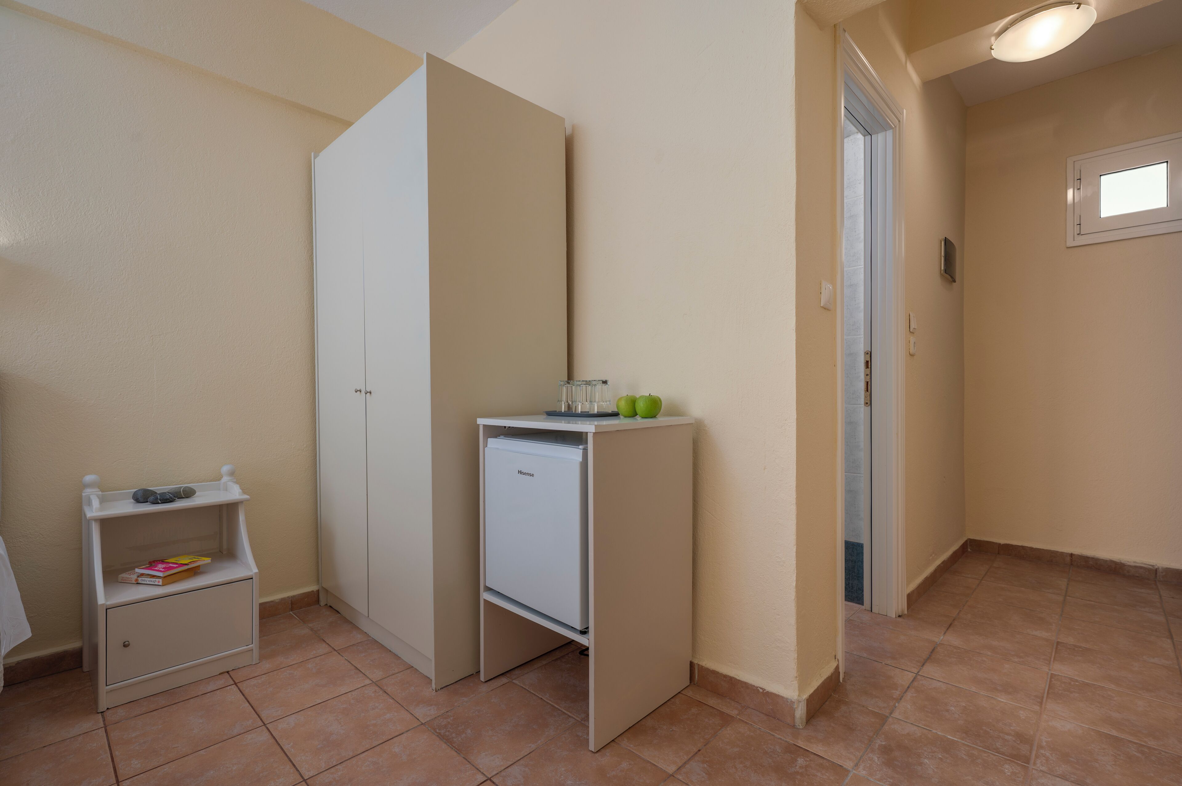 A small room with a white refrigerator, a small table with a book, and a cabinet.