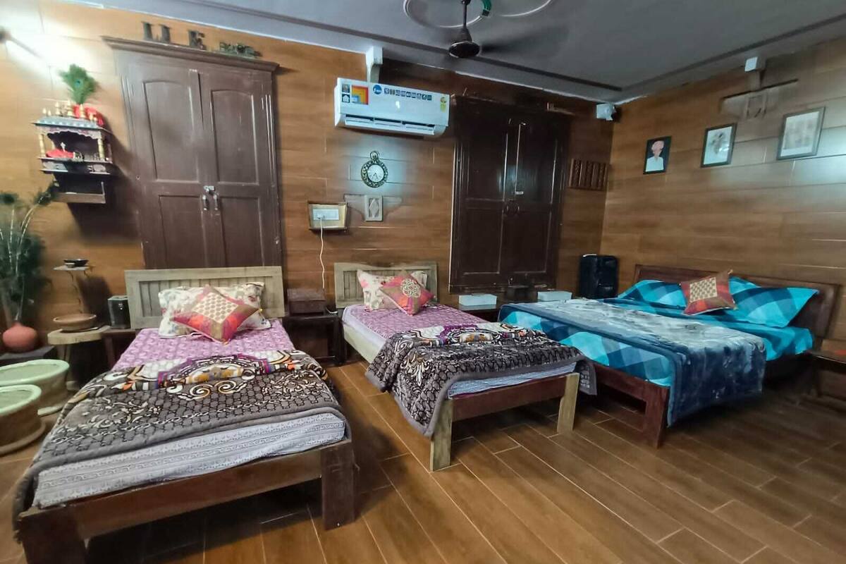 Une pièce comprenant trois lits en bois, une armoire, une horloge et un climatiseur fixé au mur.