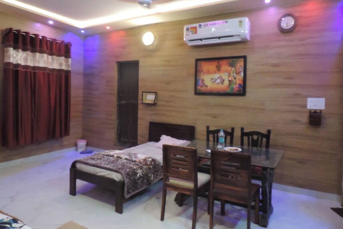 Une chambre à coucher avec un lit, une table et des chaises, un climatiseur et une horloge au mur.