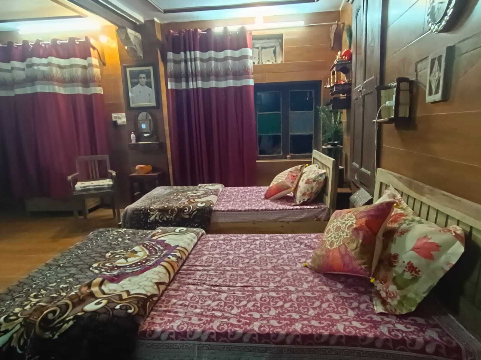 A room with two beds, a chair, a small table, and a window.