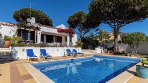 A swimming pool with lounge chairs, a white building with a red-tiled roof, and surrounding greenery. - Roseus Villa, Galé, Algarve (Guia)