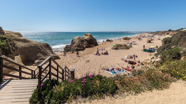 A beach with a wooden staircase leading down to the sand, large rocks, and people sunbathing. - Roseus Villa, Galé, Algarve (Guia)