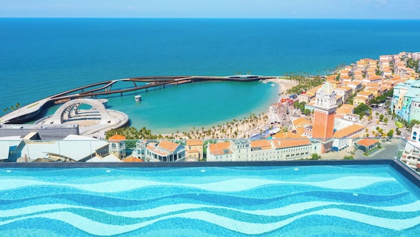 A coastal resort with a swimming pool, a pier, and beachfront villas.