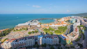 An aerial view of a coastal city with historic buildings, a marina, and a large open plaza.