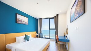 A hotel room with a large bed, a desk, and a view of the ocean.