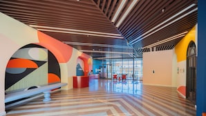 A modern lobby with a check-in desk, seating area, and a large glass entrance.