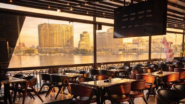 A modern restaurant with a view of a city skyline. - YOU Cairo Nile View Hotel (Cairo)