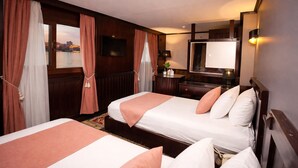 A hotel room with two beds, a desk, a mirror, and a view of a cityscape. - YOU Cairo Nile View Hotel (Cairo)