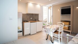 A compact kitchen with white cabinets, a small refrigerator, and a dining area with a table and chairs. - La Bastide Bleue La Ciotat (La Ciotat)