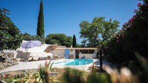 A modern outdoor pool area with a stone wall, lounge chairs, and a pergola with umbrellas. - La Bastide Bleue La Ciotat (La Ciotat)
