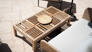 A wooden table with a circular center piece, a wicker chair with a cushion, and a stone-tiled floor. - La Bastide Bleue La Ciotat (La Ciotat)