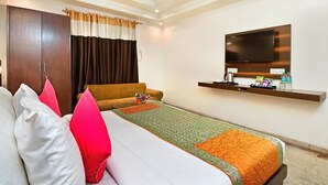 A hotel room with a bed, a TV, a shelf with toiletries, and a wardrobe.