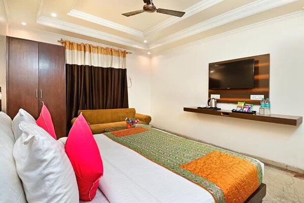 Una habitación de hotel con cama, televisor, repisa con artículos de aseo y armario.