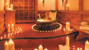 A spa room with a circular hot tub, candles, and wooden decor. - Hotel Salnerhof Ischgl (Ischgl)