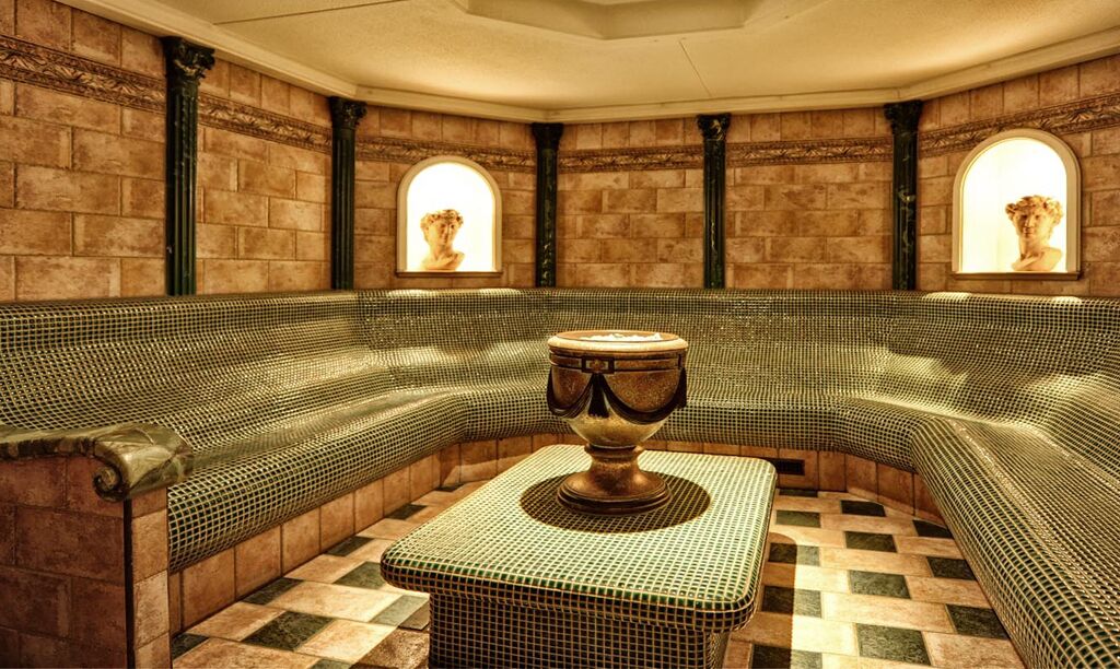 A room with a checkered floor, a curved bench, and two arched windows with sculptures.
