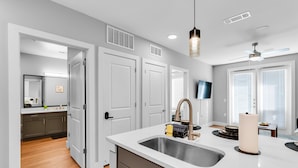 A modern kitchen with a white countertop, stainless steel sink, and a ceiling fan. - Charming 1-bedroom apartment in Fort Worth with WiFi, AC, fitness room (Fort Worth)