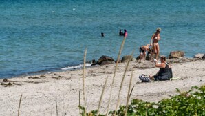 Une plage où des gens se prélassent au soleil et se baignent.