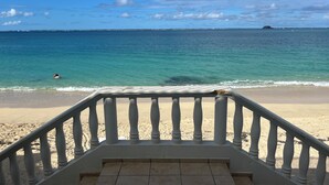 A beach view from a balcony with a railing, ocean, and distant land. - Modern apartment in beachfront residence - hill view (Grand-Case)
