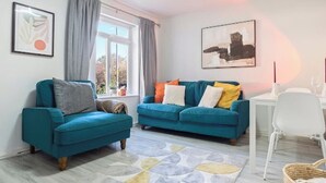 Un salon avec deux canapés de couleur turquoise, une table blanche et une fenêtre avec des rideaux.