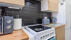 Une cuisine compacte équipée d’une cuisinière à gaz, d’un grille-pain et d’une bouilloire.