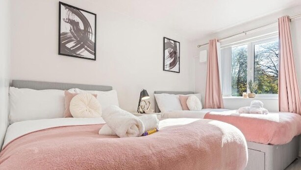 Une chambre d’hôtel avec deux lits, une grande fenêtre avec des rideaux et des œuvres d’art accrochées aux murs.