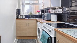 Une cuisine compacte équipée d’un lave-linge, d’une cuisinière et d’un four à micro-ondes.