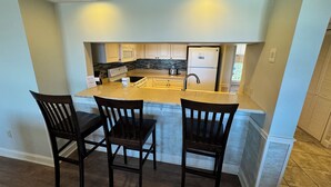 A kitchen with a central island, two bar stools, and a built-in sink. - Gorgeous 2 bedroom villa overlooking Shelter Cove Harbour with pool and spa (Hilton Head Island)