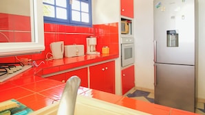 Eine Küche mit roten Schränken, einem Edelstahlkühlschrank und einer Mikrowelle.