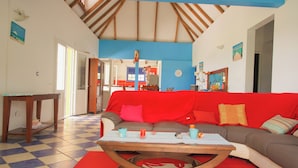Ein Wohnzimmer mit Schachbrettmuster-Boden, einer roten Couch, einem Holztisch und einer blauen Wand.