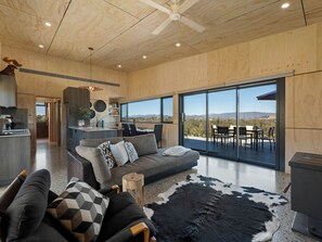 Amplia sala de estar con un sofá grande, una mesa de comedor y vistas al exterior.