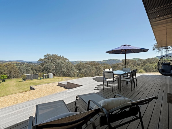 Una terraza con mobiliario exterior, una mesa y una sombrilla.