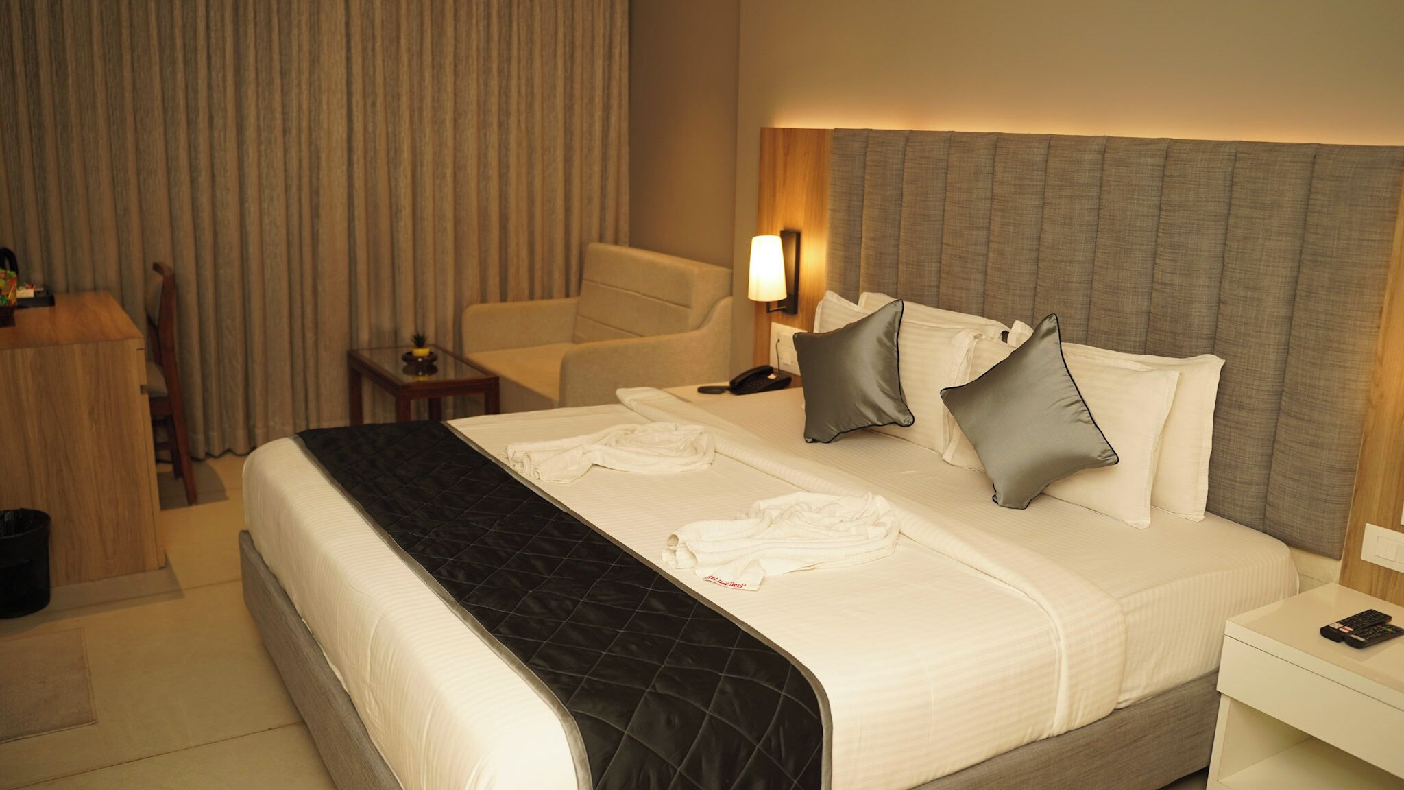 Una habitación de hotel con una cama grande, un escritorio, una silla y una lámpara.