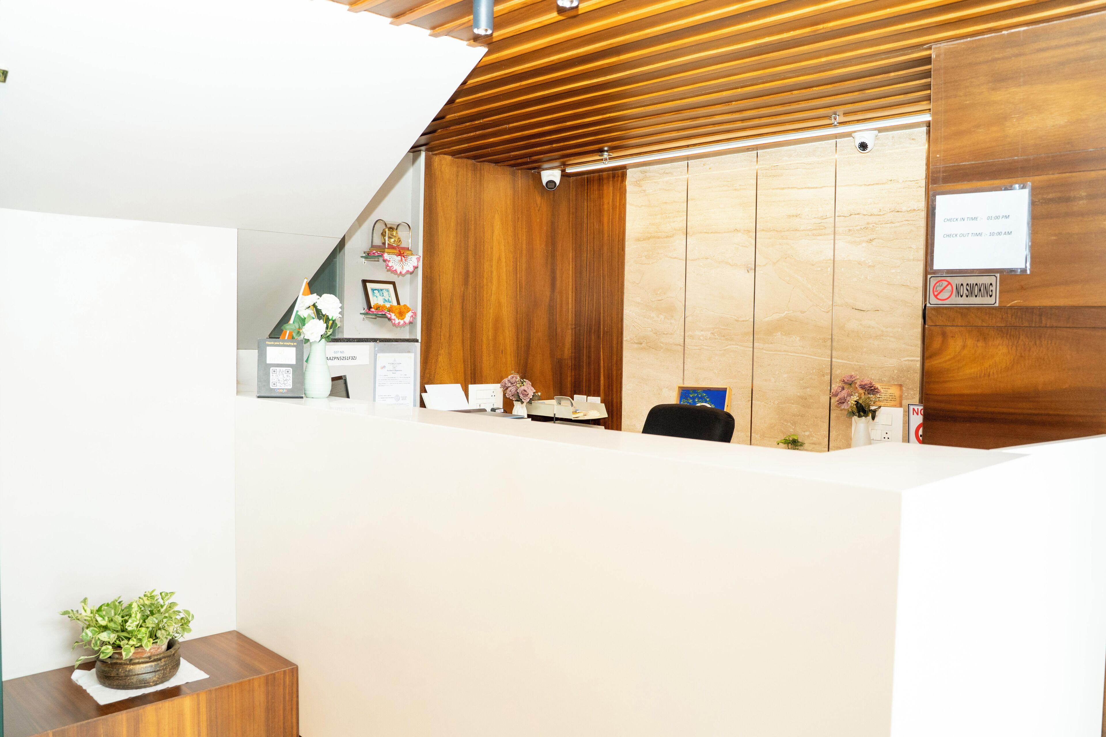 A reception desk with a wooden panel wall, a check-in/out sign, and a no smoking sign.