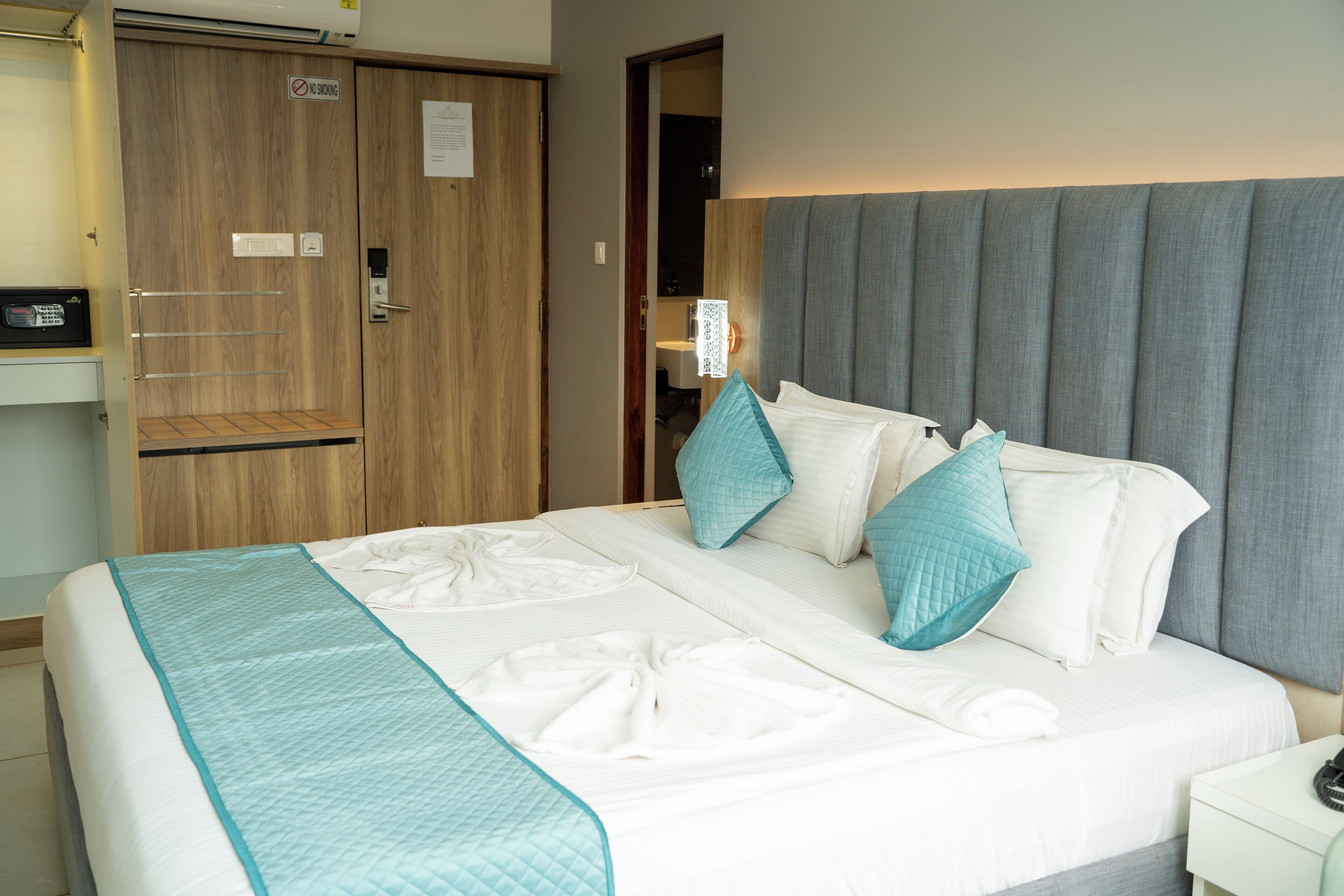 A hotel room with a bed, a wardrobe, and a bedside table.